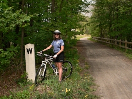 Zhanna stands next to a well preserved whistle post near a road crossing.
