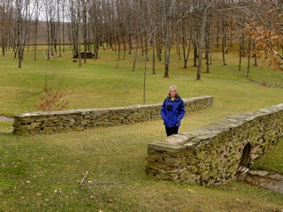 Zhanna stands on the wide stone bridge leading into the park.