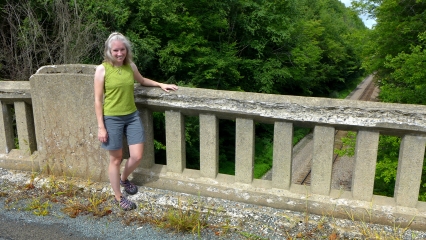 Zhanna stands by the crumbling bridge rail.