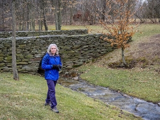 Zhanna stands on mucky ground near the stone bridge