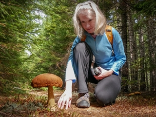 Zhanna examines a large mushroom growing along the trail.
