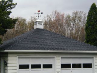 The chicken sits on top of a neighbor's garage.